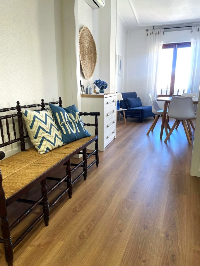 Sala de estar con bancos de madera, cojines decorativos y mesas modernas.